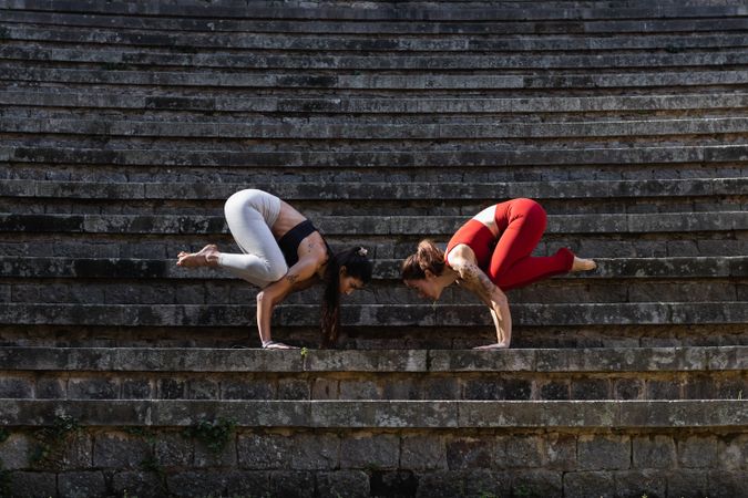 Slender women practicing yoga in crow pose on mat