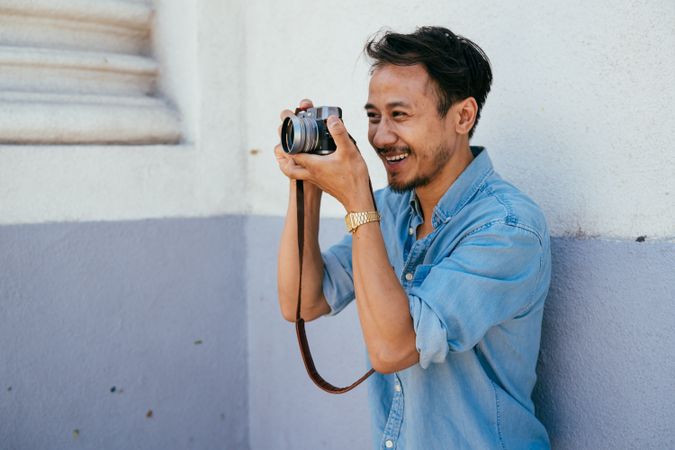 Male photographer laughing and taking photos with digital camera