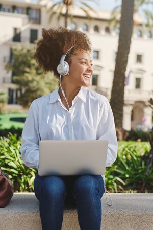 Smiling Black woman working on netbook on street