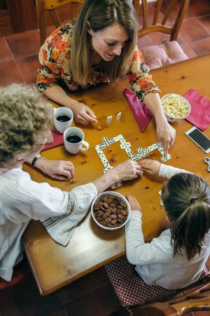 Top view of three female generations playing domino