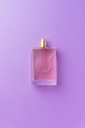Pink perfume over purple background