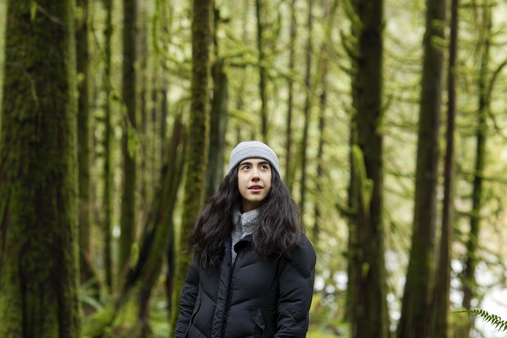 Contemplative young woman in the woods looking up