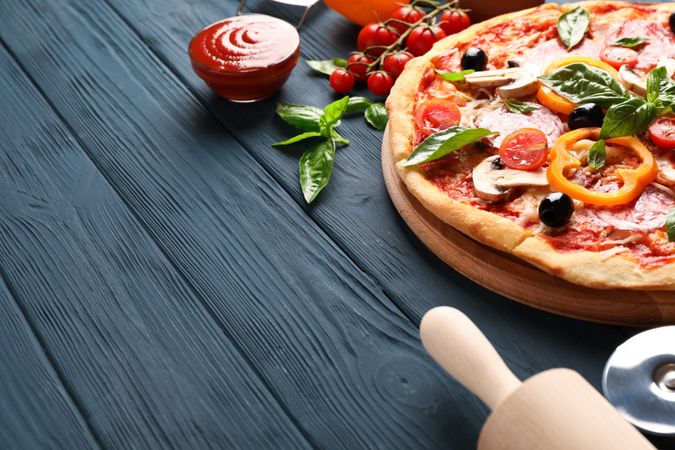 Delicious pizza and ingredients on wooden background, copy space