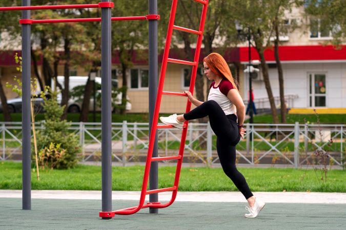 Woman lifting leg on outdoor ladder during workout