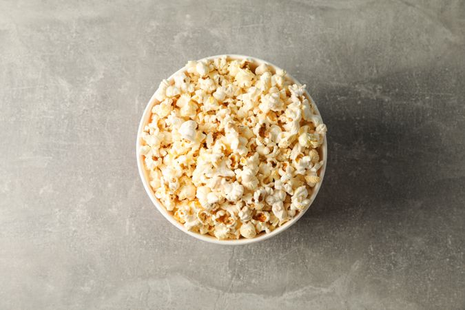 Bucket with popcorn on grey background, space for text