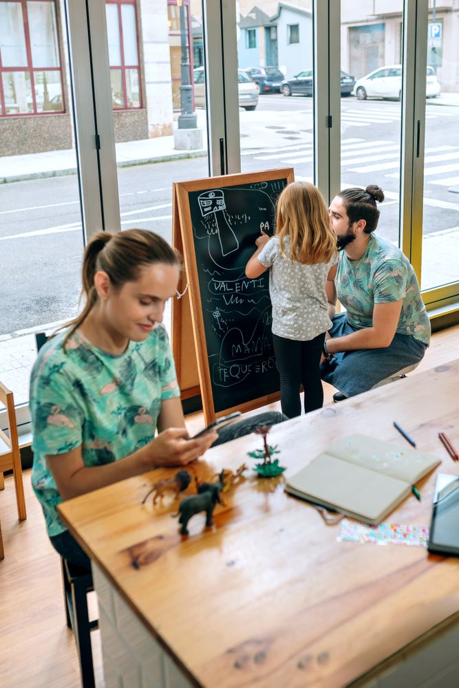 Restaurant owners managing family and work balance with daughter drawing on board
