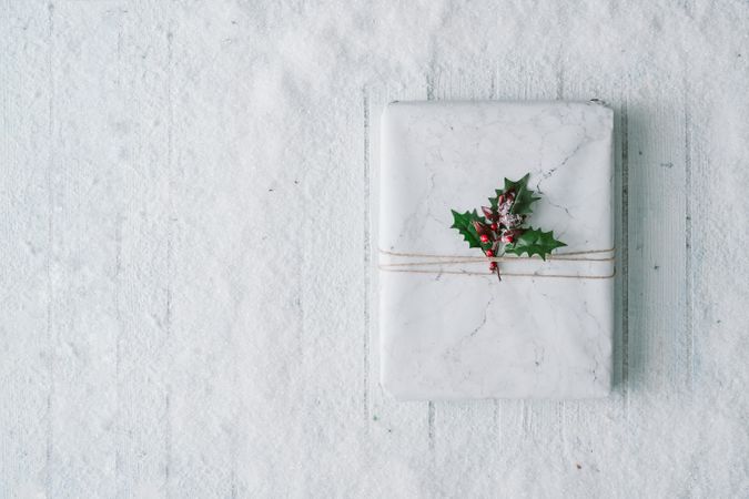 Wooden table background with snow and  wrapped present and mistletoe