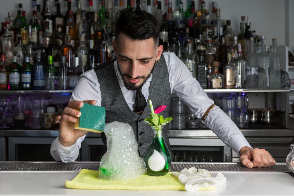 Bartender preparing an alcoholic beverage with foam in clear glass