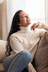 young woman sitting on sofa near window with warm light