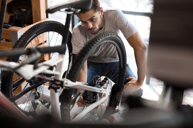 Man concentrating and inspecting a bicycle wheel for alignment