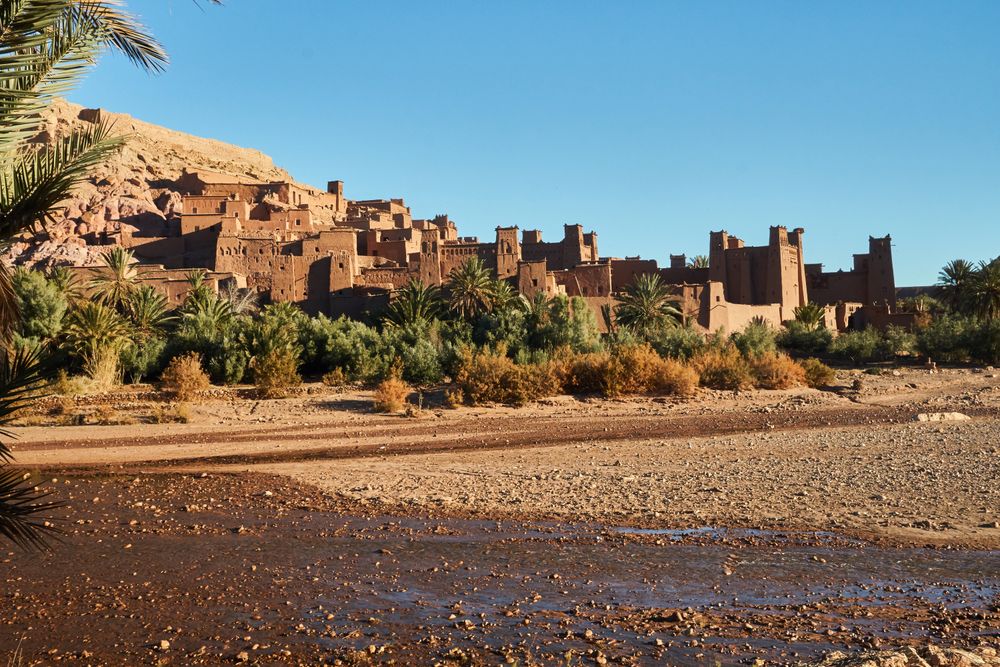 Ancient stone buildings near palms and water