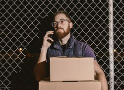 Courier with carton waiting client on street in evening
