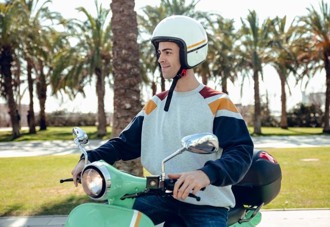 Man in motorcycle helmet sitting on bike and smiling