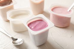 Composition with plastic cups with yogurt on table