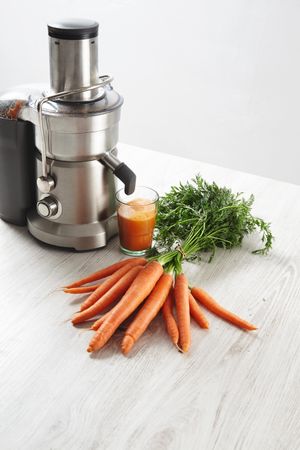 Juicer and carrots with freshly made juice