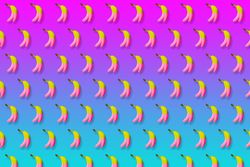 Pink and yellow bananas in rows on gradient pink to blue background
