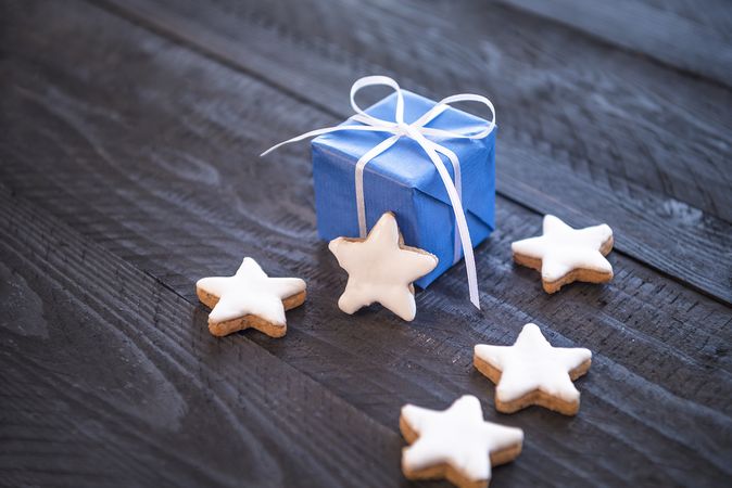 Gift wrapped in blue paper next to star shaped cookies