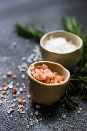 Close up salt bowls and rosemary on kitchen counter