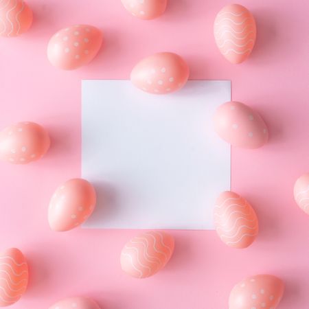 Pink Easter eggs on pink table wit paper card in center