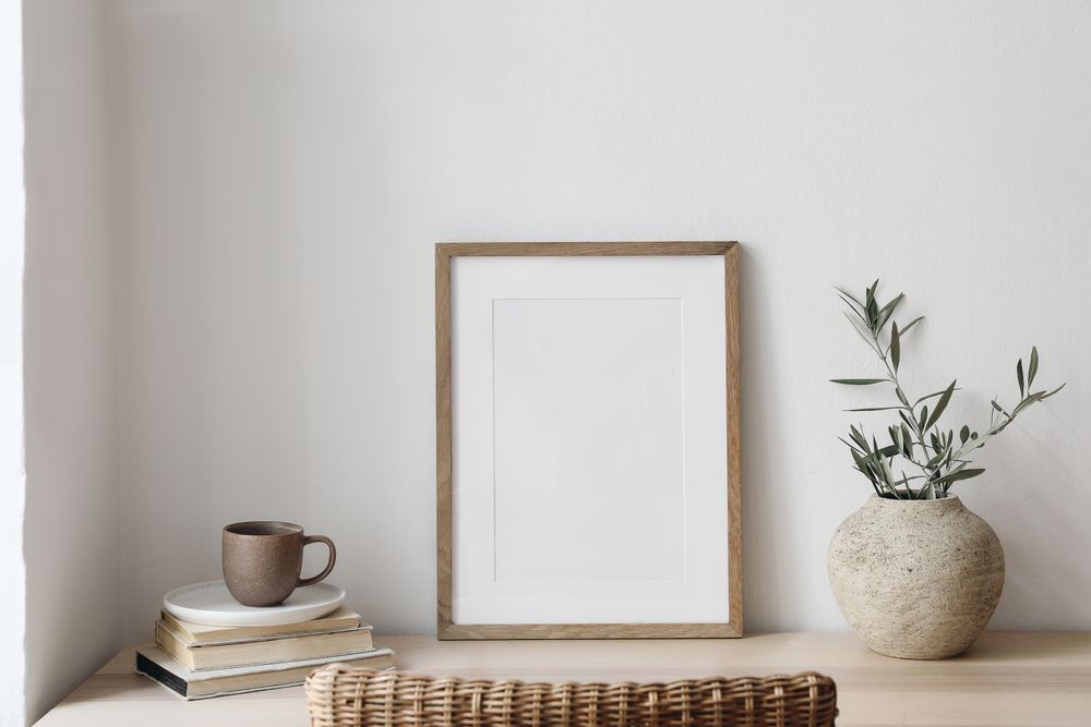 Poster frame on neutral table with vase of branches and mug of coffee