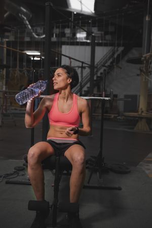 Smiling woman with bottle of water in gym
