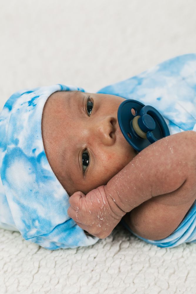 Newborn baby wrapped on soft blanket with pacifier