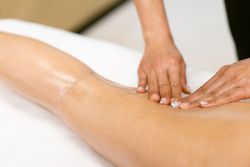 Skilled masseuse giving a hamstring massage to a woman