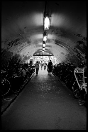 Grayscale photo of people walking through tunnel