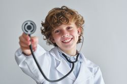 Cheerful boy with stethoscope in medical uniform