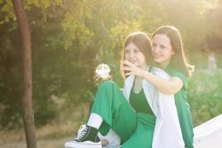 Mom and teenage daughter drink soft drinks on walk