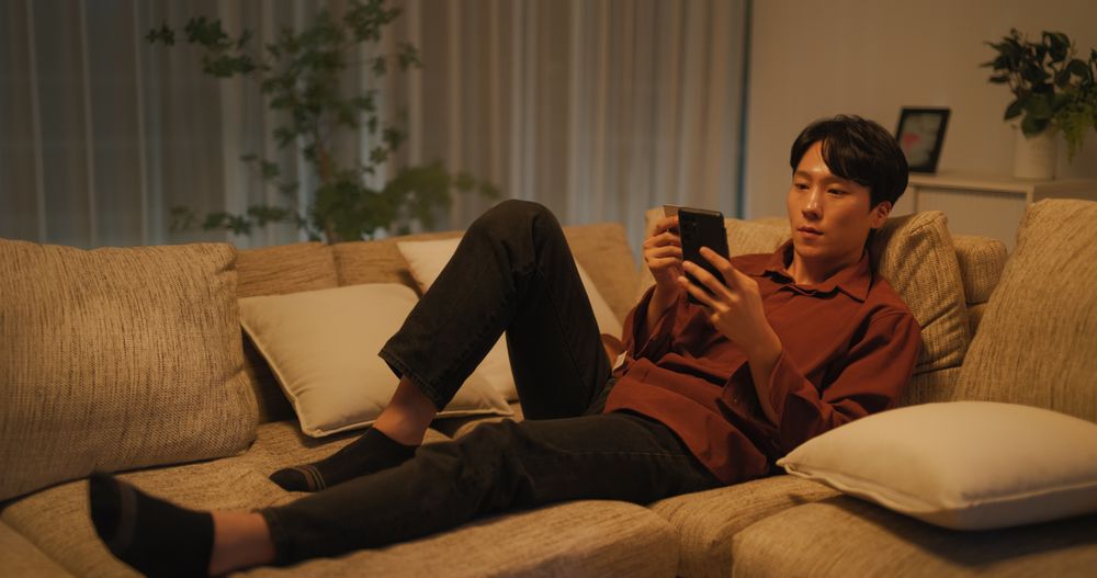 Young South Korean Man Browsing Online Streaming Service Application in a Cozy Living Room