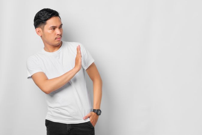 Asian male in grey studio gesturing “no” to the side with copy space