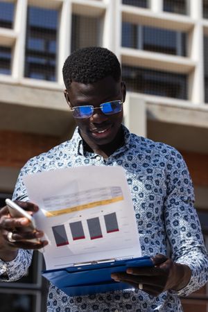 Black businessman with graphics on paper in town