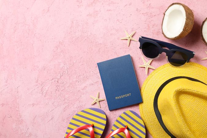 Summer travel accessories on pink background, space for text