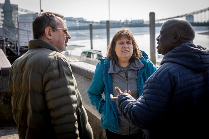 Two men and a woman talking by the river