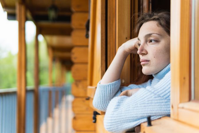 Serene woman relaxing on terrace of house in countryside