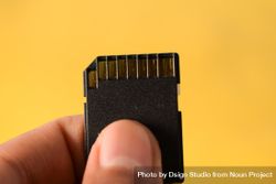 Close up of SD card in hand with yellow background 0KMEzA
