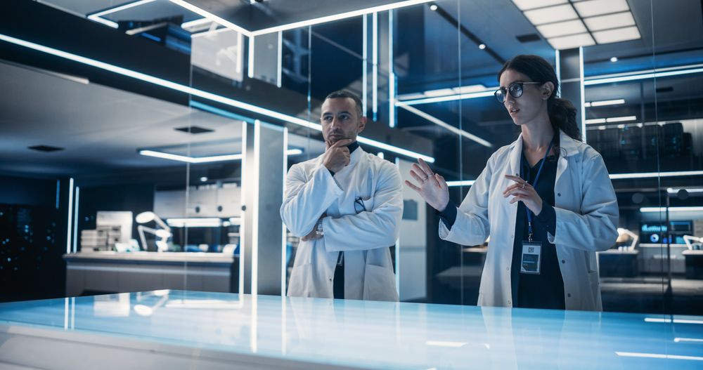 Multiethnic Male And Female Scientists Standing In the High-Tech Laboratory Next to The Table.