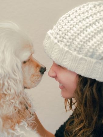 Teen in hat playing with dog