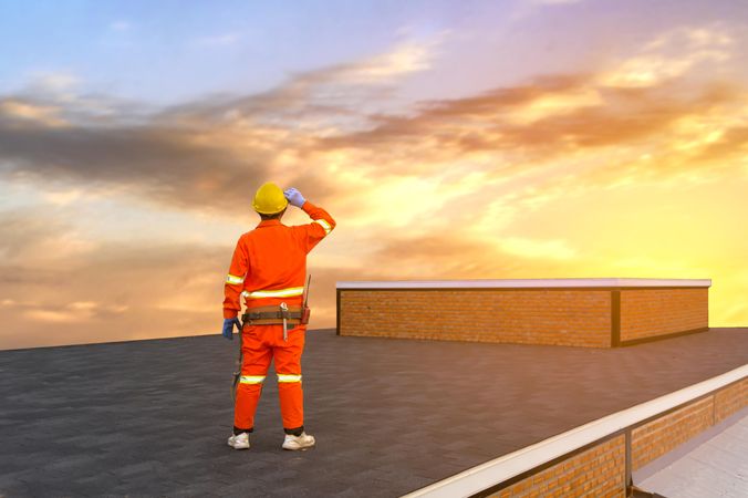 Back view of man with yellow bump hat standing on the roof