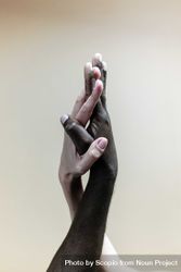 Black hand and white hand touching against light background 0gqX84