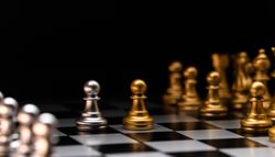 Focused pawn. Silver chess pieces and golden rivals.