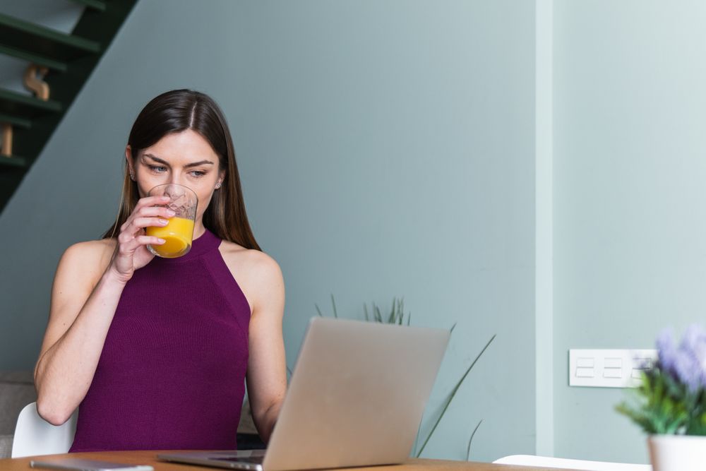 Cheerful woman browsing laptop in living room