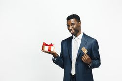 Smiling Black man holding a present wrapped in gold paper and a credit card