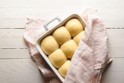 Uncooked bread buns in a ceramic tray