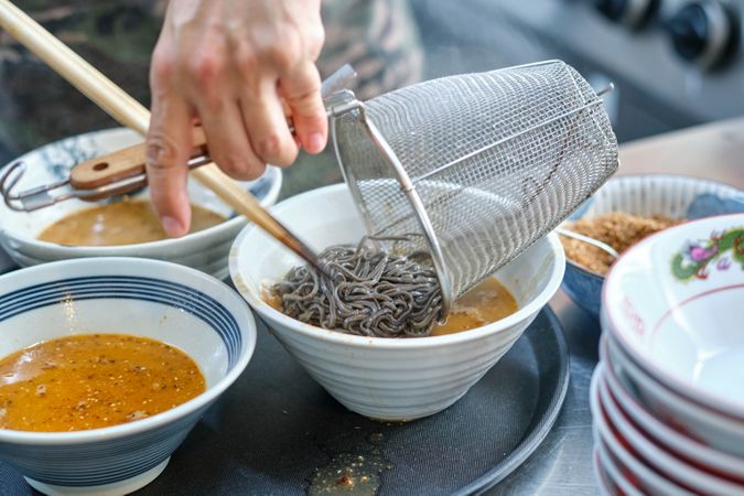 Chef cooking soup with soba noodles in bowl