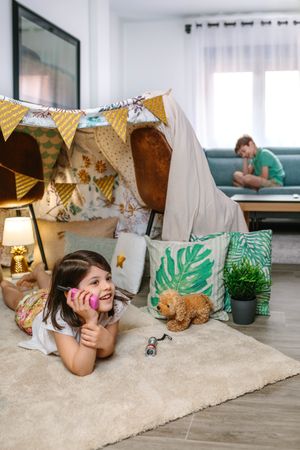 Two happy children talking with walkie-talkie at in cozy tent. Vacation camping at home concept.