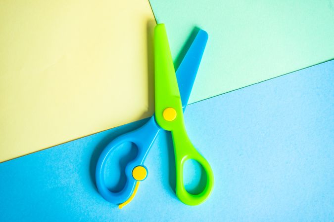 Blue & green children's scissors on paper background