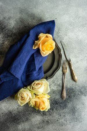 Fresh yellow rose surrounding dark plate on counter