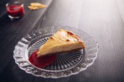 Baked cheesecake with red jam in glass plate